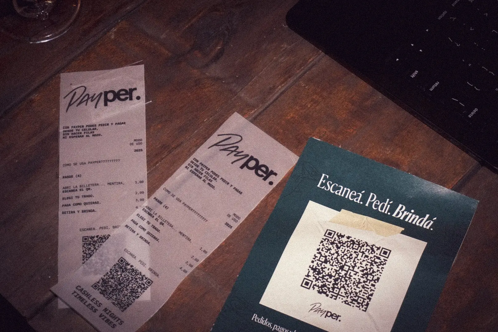 Payper receipts and a table card with a QR code that reads Escaneá. Pedí. Brindá.