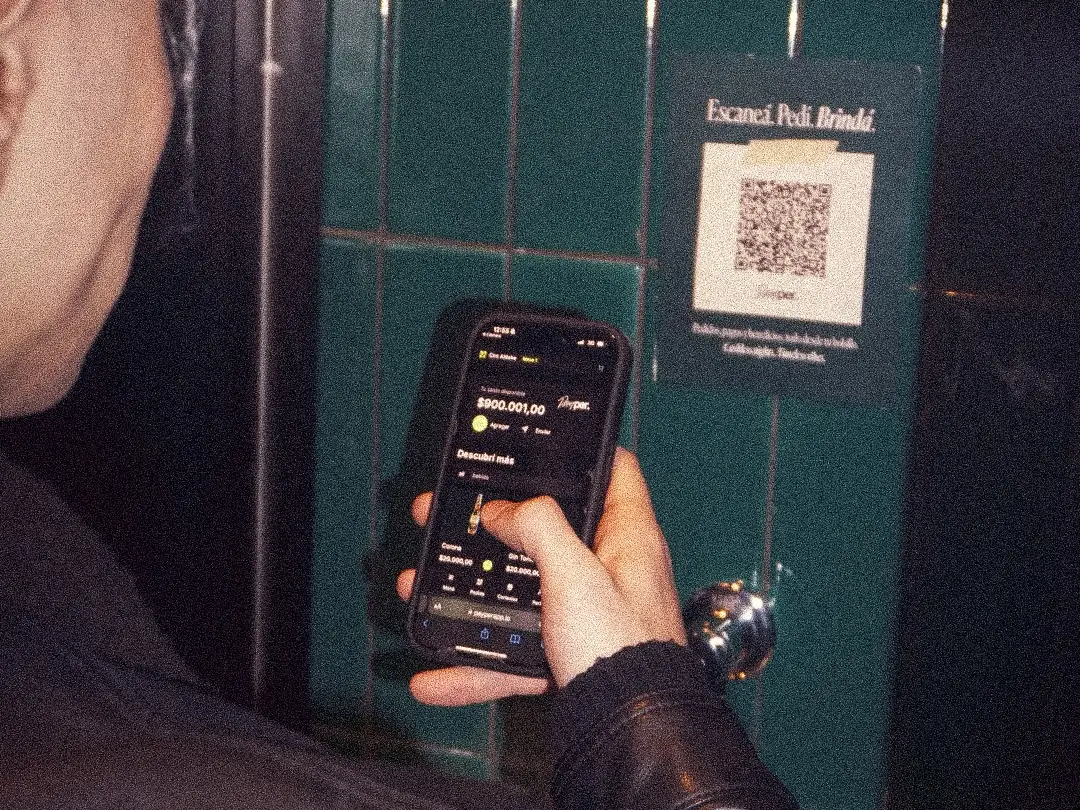 A guest scanning a Payper QR code on the wall of a bar with their phone